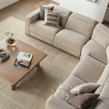 Beige sectional sofa with patterned cushions in a living room setting.